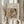 May include: Person in cream ruffled sleeves holding framed reproduction of Renoir's impressionist painting showing woman embracing young child in soft pastels. Light wood frame with beige mat, displayed against white curtained window with dried pampas grass bundle visible to left side.
