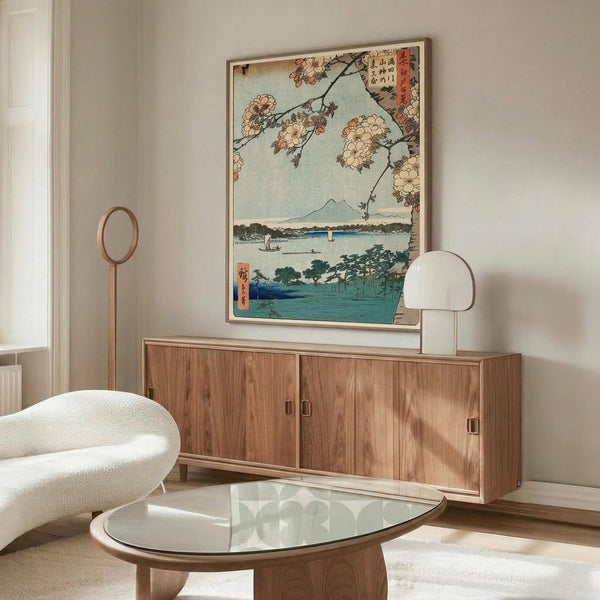 May include: Japanese woodblock print artwork showing cherry blossoms framing a lake scene with Mount Fuji in background, displayed above a mid-century modern walnut credenza in minimalist living room with cream walls, white sculptural chair, glass oval coffee table, and modern table lamp