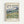 May include: Framed museum-style poster featuring Van Gogh's swirling landscape painting with golden wheat fields, rolling green hills, and dramatic blue sky with white clouds. The poster displays "VAN GOGH" in large letters at top, "Van Gogh Museum 1889" header, the colorful artwork in center, and descriptive text below reading "Van Gogh's vivid canvases capture the beauty and chaos of life" and "Landscape from Saint-Rémy". Light wood frame against white wall