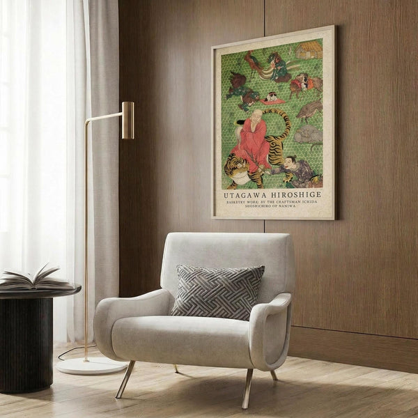May include: Japanese woodblock print artwork featuring figure in coral robes seated with tiger among various animals on green geometric background, displayed in light wood frame on warm wood paneled wall above beige upholstered armchair with geometric patterned pillow, brass floor lamp and dark round side table with open book nearby