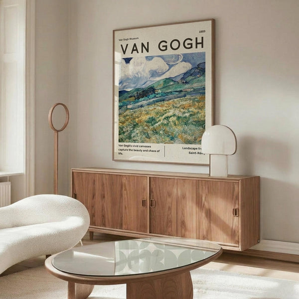 May include: Van Gogh museum poster featuring swirling landscape with golden wheat fields, rolling green hills, and dramatic cloudy blue sky, displayed above wooden mid-century credenza with brass hardware. White curved chair and glass-top oval coffee table visible in bright, minimalist room with cream walls and natural lighting.