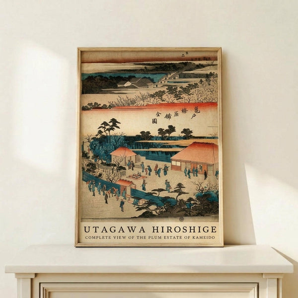 May include: A framed Japanese woodblock print reproduction displayed on a light wooden shelf against a white wall. The artwork features a traditional landscape scene with buildings, trees, people in blue robes, and coral-colored rooftops in muted blues, oranges, and earth tones. Japanese characters appear in the upper right corner, with "UTAGAWA HIROSHIGE" and English text below the image. The print is housed in a thin natural wood frame.