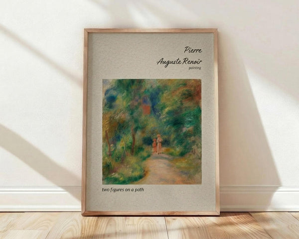 May include: Framed poster print of Pierre Auguste Renoir's impressionist painting showing two small figures walking along a winding path through lush green foliage and trees. The artwork features soft brushstrokes in greens, blues, yellows and coral tones. The print has a beige mat border with black text identifying the artist and title. Natural wood frame rests against white wall on light wooden floor with gentle sunlight shadows.