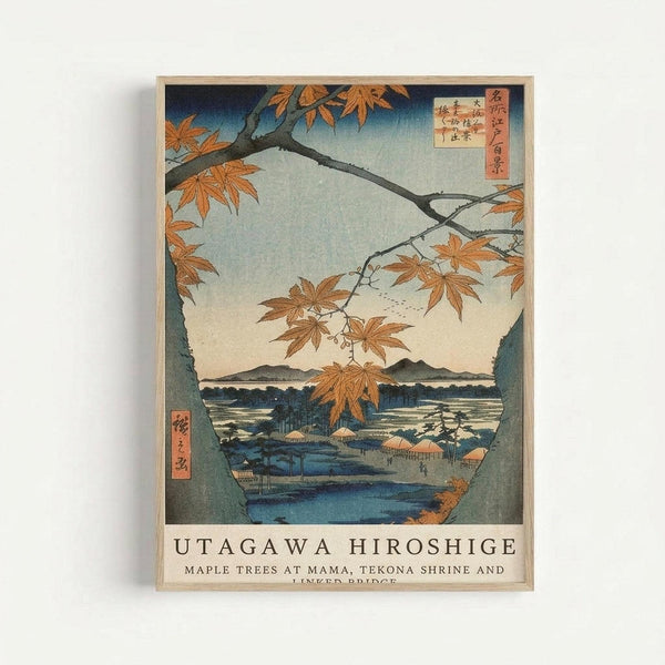 Japanese woodblock print featuring autumn maple trees with orange-red leaves framing a serene lake view with distant mountains. The artwork shows traditional ukiyo-e style with blue water, beige sky, and small buildings along the shoreline. Red Japanese text cartouches appear in upper right and lower left corners. The print is displayed in a thin wooden frame against a white wall, with the artist's name and artwork title printed below the image in black text.