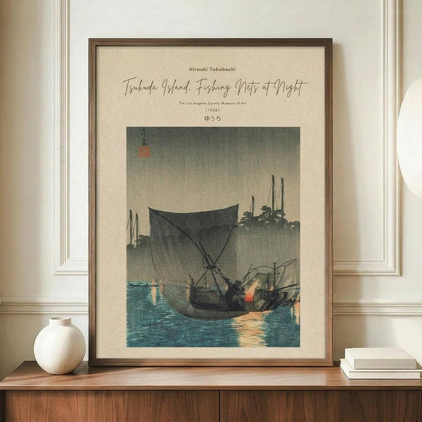 May include: Framed vintage Japanese woodblock print showing fishing boats with nets at twilight, displayed on wooden sideboard next to white ceramic vase and books. Print features muted blues, grays, and warm orange reflections on water with traditional calligraphy in upper corner. Cream matting in natural wood frame against white paneled wall creates serene interior setting.