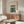May include: Japanese woodblock print poster in wooden frame showing fishing boats at twilight, displayed above walnut credenza in modern living room with cream walls, white sculptural chair, glass coffee table, and minimalist decor