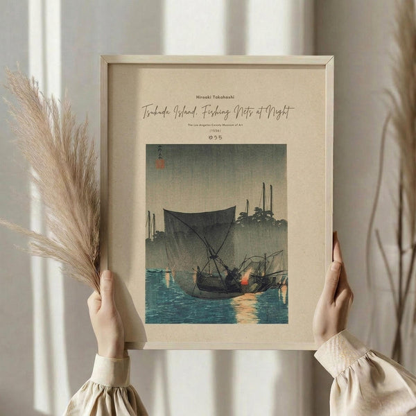 May include: Person in cream outfit holding framed Japanese woodblock print showing fishing boats at dusk with turquoise water and misty gray sky, alongside dried pampas grass stems against white curtained window background