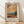 May include: Framed poster print featuring Van Gogh-style landscape with golden wheat field, tall dark cypress trees, rolling hills and dramatic swirling orange sunset sky. Text reads "Vincent Van Gogh" with French description and quote about dreams and painting. Light wood frame with cream matting, displayed on wooden floor against white wall with soft natural lighting casting diagonal shadows.