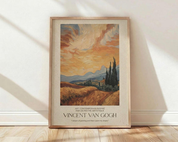 May include: Framed poster print featuring Van Gogh-style landscape with golden wheat field, tall dark cypress trees, rolling hills and dramatic swirling orange sunset sky. Text reads "Vincent Van Gogh" with French description and quote about dreams and painting. Light wood frame with cream matting, displayed on wooden floor against white wall with soft natural lighting casting diagonal shadows.