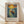 May include: Framed poster print featuring a person standing in a wooden boat on swirling blue water beneath a dramatic golden sun and colorful sky, rendered in Van Gogh's distinctive post-impressionist style with bold brushstrokes. The artwork is displayed in a light wood frame with cream matting against a white wall with natural sunlight casting diagonal shadows. Text appears below the image crediting Vincent Van Gogh with an inspirational quote about dreaming and painting.