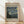 May include: Framed museum-style poster featuring Van Gogh's Starry Night painting with swirling blue sky and yellow stars, displayed on light wooden floor against white wall with natural sunlight shadows. Beige background with black text reading "VAN GOGH" and "1889" at top, artwork description and title at bottom. Natural wood frame with visible grain texture.
