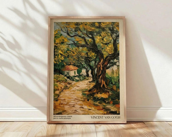 May include: Framed Van Gogh-style print showing a gnarled olive tree with swirling yellow-green foliage beside a winding dirt path leading to a small white house with red roof. The painting features thick, expressive brushstrokes in golden yellows, deep greens, and earth tones. Light wood frame rests against white wall on natural wood flooring with diagonal window shadows crossing the scene.