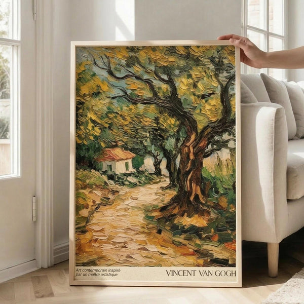 May include: A framed Van Gogh-style poster showing an olive tree with thick, gnarled trunk and golden-green foliage painted in heavy impasto brushstrokes. A small house sits in the background along a winding path. The artwork features warm yellows, greens, and earth tones in the characteristic swirling style. Someone holds the light wood-framed print in a bright living room with white walls, large windows, and a beige sofa.