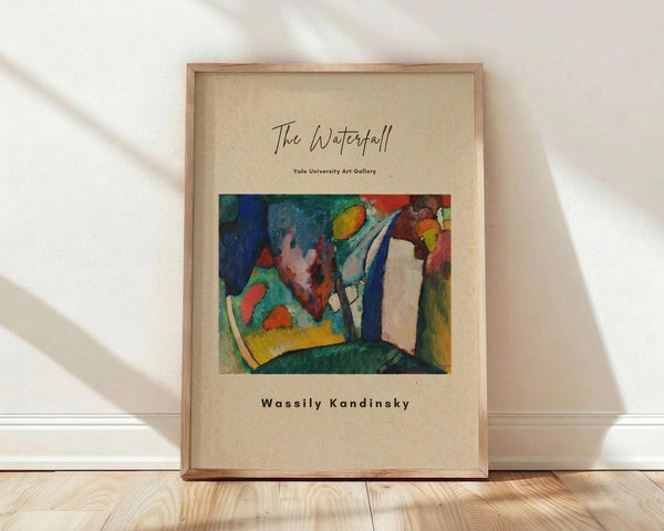 May include: Framed art print leaning against white wall on light wooden floor with natural window shadows. Features abstract expressionist painting with vibrant blues, greens, reds, and yellows in organic flowing shapes. Beige poster background with elegant script title and artist name in black text. Natural wood frame surrounds cream-colored print in minimalist room setting.