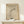 May include: Framed beige poster with abstract black curved lines and a circle, displayed on light wood surface with small wrapped gift box. Modern minimalist wall art in natural wood frame against cream wall with soft lighting and shadows.