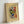 May include: Framed abstract art poster with vibrant swirling colors in green, blue, red, yellow and orange on cream background, displayed in light wood frame leaning against white wall. The artwork features dynamic brushstrokes and geometric shapes in Kandinsky's distinctive abstract expressionist style.