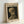 May include: Framed poster print of Van Gogh's skeleton with cigarette painting displayed on white wall. The artwork shows a skull in profile with a lit cigarette against dark background, printed on cream-colored paper with museum-style typography. Light wooden frame casts subtle shadow on clean white surface below.