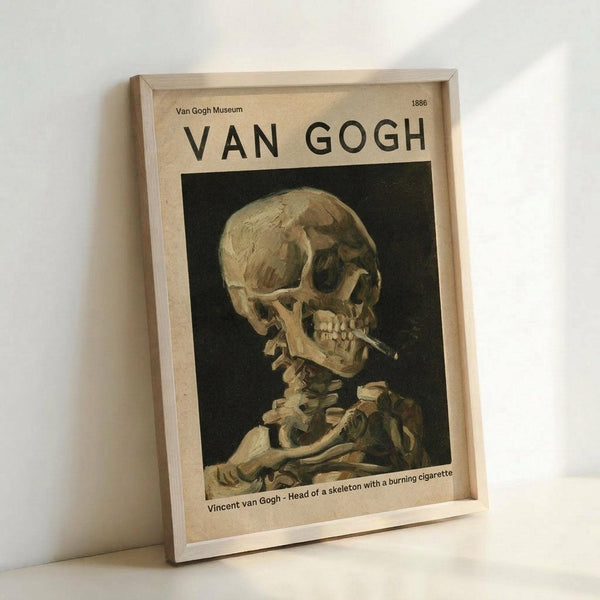 May include: Framed poster print of Van Gogh's skeleton with cigarette painting displayed on white wall. The artwork shows a skull in profile with a lit cigarette against dark background, printed on cream-colored paper with museum-style typography. Light wooden frame casts subtle shadow on clean white surface below.