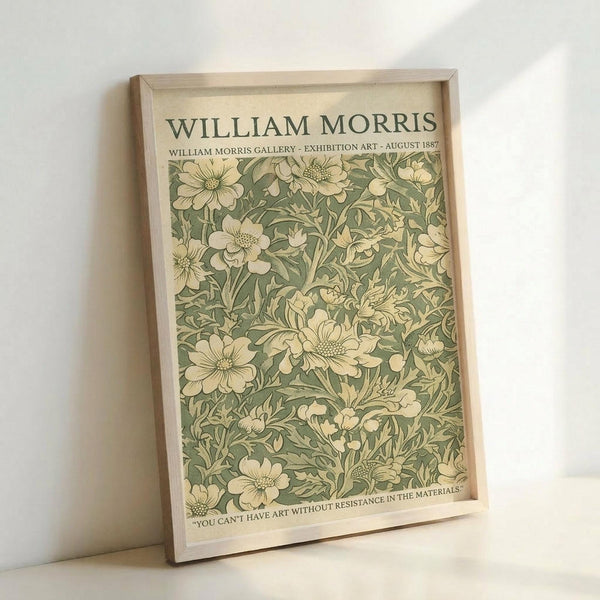 May include: Framed vintage-style botanical poster with sage green and cream floral pattern featuring detailed flowers and leaves. Light wood frame displayed against white wall, showing William Morris Gallery exhibition text from August 1887 with quote about art and materials at bottom.