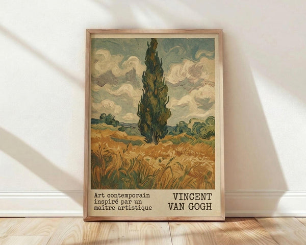 May include: Framed art print featuring a tall dark cypress tree in a golden wheat field under swirling cloudy sky, displayed in light wood frame against white textured wall on wooden floor. Print shows Van Gogh's characteristic bold brushstrokes and earthy color palette of greens, golds, and cream tones with French text at bottom.