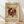 May include: Framed poster with abstract geometric design in dark red on cream background, featuring circular forms with radiating lines and scattered dots in modernist style, displayed in light wood frame against white wall on wooden floor with natural lighting