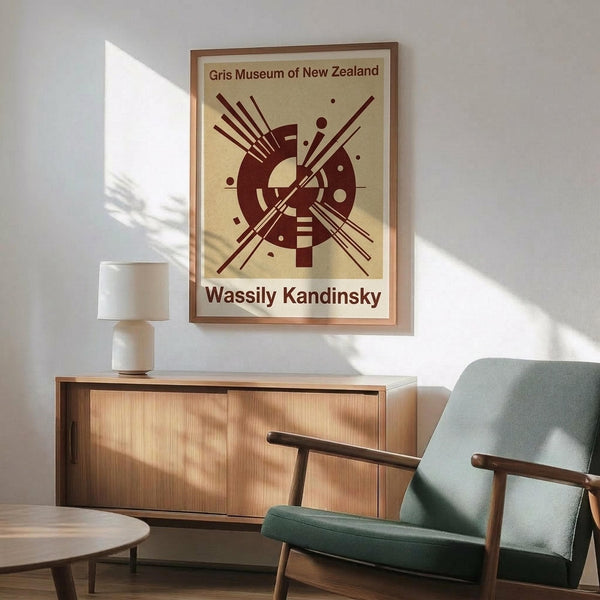 May include: Framed abstract art poster with burgundy geometric design featuring circular and linear elements on cream background, displayed above wooden sideboard with table lamp in modern living room setting with mint green upholstered chair and natural lighting casting shadows on white wall.