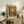 May include: Vintage-style poster featuring a brown bear in a forest of tall trees with golden sunlight filtering through, framed in light wood and displayed on a rustic wooden sideboard alongside a fern plant, ceramic vase, and books in a cozy living room setting with neutral tones and natural lighting.