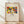 May include: Framed art print leaning against white wall on light wood floor. Print features colorful abstract artwork with red, yellow, blue, and green shapes depicting stylized figures. Text reads "The Art Institute of Chicago (1913)" at top, "Klänge" in center, and "Wassily Kandinsky" below. Natural wood frame with cream matting. Soft window light creates diagonal shadows across white fabric backdrop.