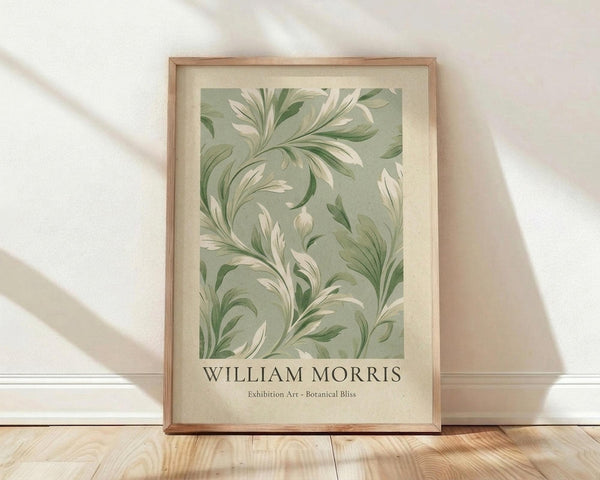 May include: Framed botanical art print featuring flowing green and cream leaf patterns in William Morris style, displayed in light wood frame against white textured wall. Soft natural lighting creates diagonal shadows across wooden floor. The decorative foliage design shows curving acanthus leaves in muted sage and ivory tones on vintage-style background.