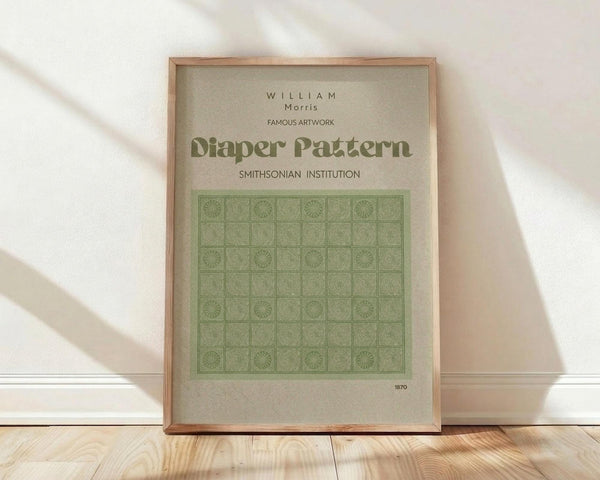 May include: Framed poster with beige background displaying green geometric grid pattern featuring repeating squares with radiating sunburst and circular motifs. Text reads "WILLIAM Morris," "FAMOUS ARTWORK," "Diaper Pattern," "SMITHSONIAN INSTITUTION," and "1870." Light wood frame sits against white wall on blonde hardwood floor with soft natural lighting creating diagonal shadows.