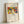 May include: Framed museum exhibition poster featuring Wassily Kandinsky's abstract artwork in vibrant primary colors - red, blue, yellow with geometric and organic shapes. The colorful composition shows dynamic movement with various forms and figures. Text reads "The Art Institute of Chicago (1913)" at top, "Klänge" and "Wassily Kandinsky" below the artwork. Light wood frame with white matting, leaning against white wall corner.