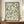 May include: Framed botanical art print with green leafy pattern on cream background, displayed on wooden sideboard next to white ceramic vase and stacked books. Features William Morris-style foliage design with flowing stems, leaves, and small buds in sage green tones. Print shown in thin brown frame against white paneled wall in elegant interior setting.