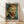 May include: Framed poster print featuring Vincent van Gogh's self-portrait with swirling blue-green background, reddish-orange hair and beard, piercing blue eyes, and dark suit jacket. Print has vintage-style border with handwritten signature and "self portrait" text. Natural wood frame leaning against white wall on light wooden floor with soft shadows.