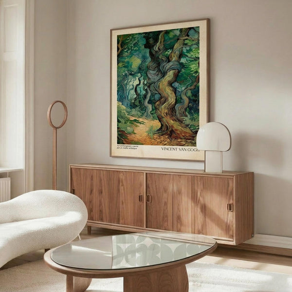 May include: A framed Van Gogh poster print of swirling cypress trees in vibrant greens and blues, displayed on a warm wood credenza in a minimalist living room with cream walls, white curved chair, glass coffee table, and modern brass floor lamp.