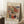 May include: Framed abstract watercolor art print with swirling brushstrokes in red, blue, green, and orange tones, leaning against white wall beside wooden side table with white coffee cup. The poster features flowing organic shapes and dynamic lines in Kandinsky's distinctive abstract style, displayed in light wooden frame on textured cream rug.