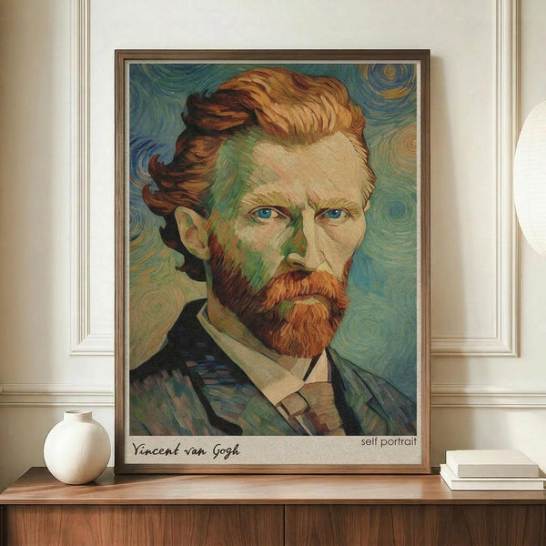 May include: Framed reproduction of Van Gogh's self-portrait showing the artist with reddish-brown hair and beard, blue eyes, and dark jacket against swirling blue-green background. The print sits on a wooden sideboard next to a white ceramic vase and books in a room with cream walls and white molding.