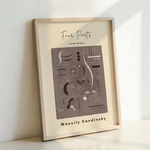 May include: Framed abstract art print leaning against white wall corner. Light wood frame contains cream poster with gray abstract geometric composition featuring curved lines, circles, rectangles and various shapes in muted tones. Artist name printed below artwork in simple black text.