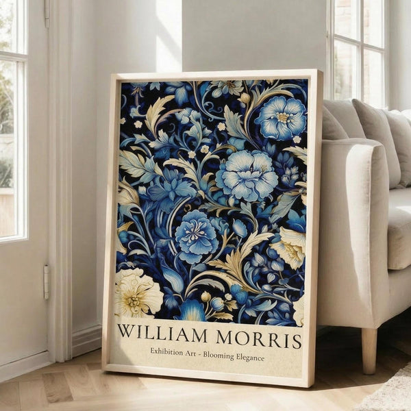 May include: Framed poster with intricate blue floral pattern on dark background featuring ornate blooms and swirling foliage in William Morris decorative style, displayed in light wood frame leaning against white wall next to beige upholstered sofa in bright, airy living room with large windows