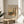 May include: Framed poster print featuring a colorful landscape painting with two tall poplar trees, winding path, and vibrant autumn colors in oranges, greens, and yellows. The print includes museum text identifying it as a Wassily Kandinsky work from The Art Institute of Chicago. Displayed on a light wood round side table next to a beige upholstered chair with plant leaves visible in soft natural lighting.