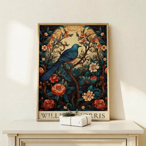 May include: Framed botanical art print featuring a blue bird perched among ornate flowering branches with red peonies and cream blooms in William Morris decorative style. Print displays in thin wooden frame on light wood console table beside small wrapped white gift box with evergreen sprig. Cream colored wall background with soft natural lighting.