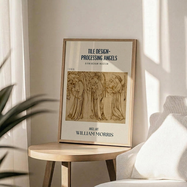 May include: Framed vintage-style poster featuring sepia-toned illustration of three robed angels in procession, displayed on round wooden side table next to beige upholstered chair. Natural lighting creates soft shadows across white walls, with green plant leaves visible in corner. Minimalist Scandinavian-inspired interior styling with neutral tones and natural wood textures.