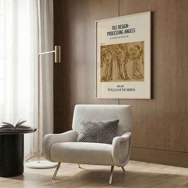 May include: Cream-colored framed poster featuring vintage angel illustration hanging on wood-paneled wall above beige upholstered armchair with geometric patterned pillow. Modern floor lamp with brass finish and round side table with open book complete the neutral-toned reading nook scene.