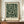 May include: Framed botanical art print with dark green background and cream-colored flowing leaves and flowers in vintage William Morris style, displayed on wooden sideboard next to white ceramic vase and books in elegant room with white wainscoting and warm lighting.