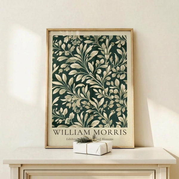 May include: Framed botanical poster with dark green background and cream-colored flowing floral pattern, displayed on light wooden console table against white wall. Small wrapped gift box with evergreen sprig sits beside the natural wood frame. Soft natural lighting creates gentle shadows on the minimalist scene.