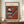 May include: Framed abstract geometric art print in warm orange and teal tones, featuring triangular and linear shapes in Kandinsky's distinctive style. The poster shows "Gris" at top with "Museum of New Zealand" and "Wassily Kandinsky" text below the artwork. Displayed on wooden sideboard alongside white ceramic vase and stacked books in modern interior with cream walls and white trim.