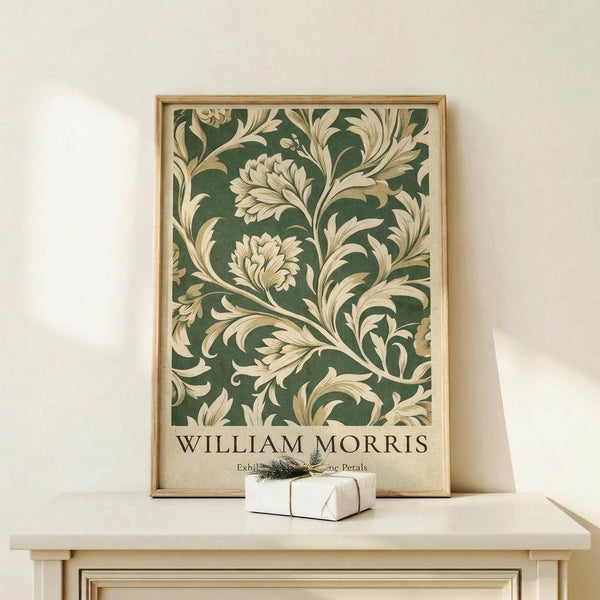 May include: Framed botanical art print with green background and cream-colored ornate floral scrollwork pattern displayed on light wood console table. Small white wrapped gift with green sprig sits beside the golden wood-framed poster against neutral beige wall.