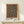 May include: Framed poster featuring an ornate carpet design with intricate floral patterns in teal blue center and burgundy border, displayed on a light wood console table alongside a small white gift box with twine, against a cream colored wall in minimalist home setting.