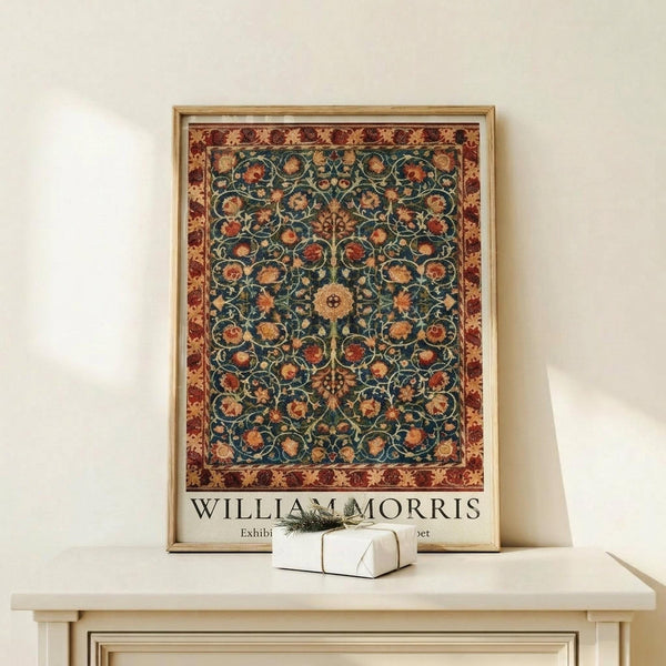 May include: Framed poster featuring an ornate carpet design with intricate floral patterns in teal blue center and burgundy border, displayed on a light wood console table alongside a small white gift box with twine, against a cream colored wall in minimalist home setting.