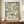 May include: Framed botanical art print with flowing green and cream leaf patterns in William Morris style, displayed on wooden console table beside white ceramic vase and stacked books against cream wall with white molding