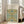 May include: Framed botanical art print featuring William Morris floral vine pattern in blue, green and gold tones, displayed in light wood frame leaning against white wall next to beige upholstered chair in bright, airy living room setting with hardwood floors.